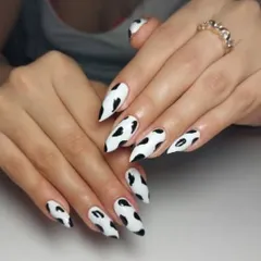 A fun and trendy cow print design on long, stiletto-shaped nails. This black and white pattern is always a stylish choice.