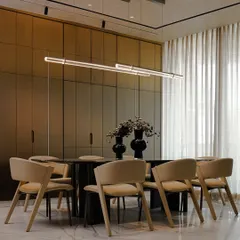 This dining area is designed to be warm and inviting, with soft beige chairs and a sleek stone tabletop. The cabinetry in the background conceals a bar, maintaining a clean, uncluttered look perfect for modern living.