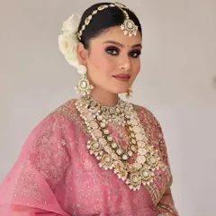 A bride looking elegant in a layered Kundan and pearl necklace set. This style is perfect for creating a sophisticated and royal bridal look, paired with a matching maang tikka and simple earrings.