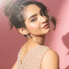 A soft and elegant portrait of Anushka Sen, with a classic updo and gentle lighting against a pink studio background.