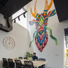 This shot highlights the scale of the custom mural, which overlooks a collaborative work table. The artwork's vibrant, tribal-inspired pattern creates a strong visual identity for the space and fosters a creative atmosphere.
