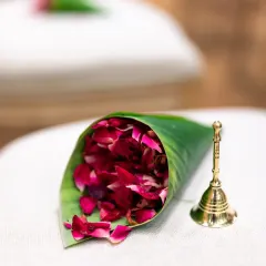 A close-up of the small details that make a wedding special: a cone of rose petals for showering the couple and a small brass bell.