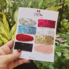Holding up a full set of our glitter barrettes. These are perfect for parties or any time you want to add a bit of glam to your look.