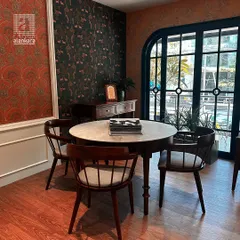 Another corner of my showroom, featuring a marble-topped dining table and wooden chairs set against a backdrop of contrasting wallpapers, showcasing my eclectic style.