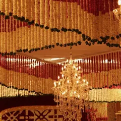 A view looking up at the intricate floral ceiling, where rows of red and yellow garlands create a vibrant pattern. A crystal chandelier hangs in the center, its light sparkling against the petals.