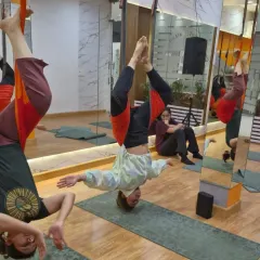 A group of flyers enjoying the benefits of a supported inversion. This pose helps lengthen the spine and release tension in the neck and shoulders. Plus, seeing your friends next to you makes it way less intimidating.