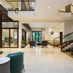This wide view shows how we create distinct zones within a large, open-plan living area. The polished marble floors run throughout, unifying the space, while furniture arrangement and architectural details like the curved staircase define different functional areas.