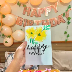 Holding up the finished birthday card against the party decorations.
