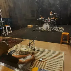 A wider view of our jam session setup. You can see the drummer in the isolation booth while I am set up on the studio floor, allowing for clean audio recording.
