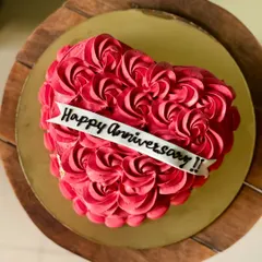 A beautiful heart-shaped anniversary cake covered in red buttercream rosettes. The "Happy Anniversary" banner across the front makes it a perfect centerpiece.