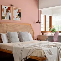 An earthy peach wall, geometric art, and a terracotta pendant lamp create a soothing synthesis in this Japandi-style bedroom. The custom rattan headboard adds a layer of natural texture, contributing to the room's warm and harmonious feel.