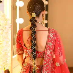 A classic bridal look featuring a long, traditional Punjabi braid. I wove golden threads and accessories through the parandi to complement the bride's red lehenga, creating a regal and authentic wedding hairstyle.