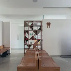 The waiting area of the Family Dental Care clinic. We used simple wooden benches and a geometric shelving unit to create a space that feels more like a calm lounge than a typical clinic waiting room.
