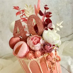 A close-up of the ruby anniversary cake, showing the shimmering rose gold details, macarons, and delicate flowers.
