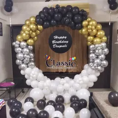A modern and chic balloon ring in black, white, silver, and gold, with a personalized center plate, perfect for a stylish home party.