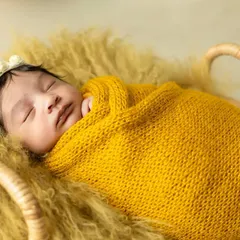 A peaceful newborn wrapped snugly in a yellow knit blanket, dreaming sweetly. I use soft textures and warm colors to create cozy and artistic newborn portraits.