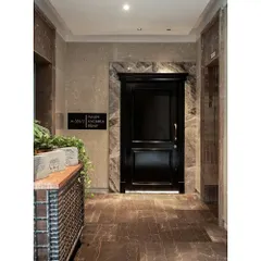 The entrance to the "Cityscape Serenity" home features a sophisticated black paneled door framed with rich marble, immediately establishing a sense of luxury and elegance.