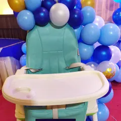 To ensure every detail matches the theme, I can also decorate key areas like the baby's high chair. Here, the chair is surrounded by balloons that match the main stage decor for the first birthday party.