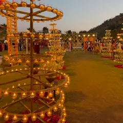 The warm glow of hundreds of diyas on traditional brass stands, lighting up the lawn for a beautiful Garba night.