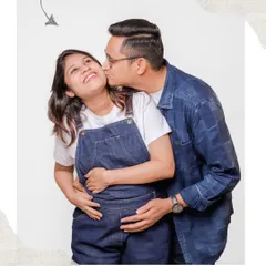 A playful and happy moment from a casual couple's maternity shoot. A gentle kiss on the cheek shows the affection and joy that surrounds this special time.