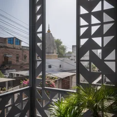 The cement block screen acts as an editor, curating views of the city. Here, it frames a distant temple dome, extending the sense of space beyond the home's physical boundaries and creating a stronger connection with the surroundings.