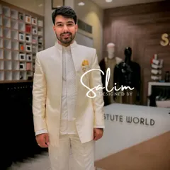 A client looking pleased in a custom-fitted ivory Jodhpuri suit. The jacket features a subtle self-striped texture and is paired with a matching inner kurta and a pop of color from the yellow pocket square.