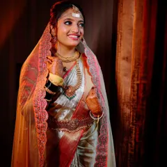 A candid bridal portrait, capturing the bride's natural smile and the beautiful details of her veil and saree under soft, flattering light.