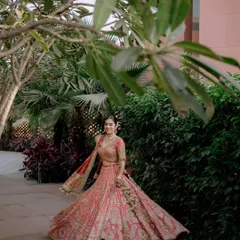 A full-length shot showcasing the magnificent bridal lehenga in all its glory. The bride looks like royalty as she takes a stroll through the beautiful venue gardens.