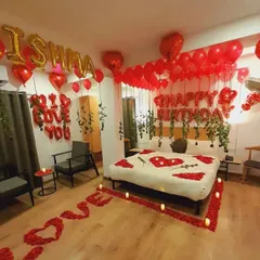 A complete room transformation for a birthday surprise, featuring a path of rose petals leading to the bed, "I Love You" messages, and a ceiling filled with red and heart-shaped balloons. This classic romantic decor is one of my most requested services.