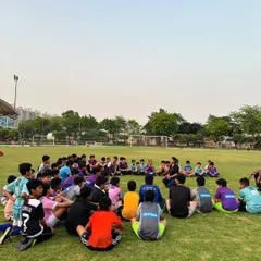 A wide view of a group physiotherapy session on our home ground. Our entire youth squad sits in a circle, learning directly from a professional about how to prevent common football injuries and maintain peak physical condition.