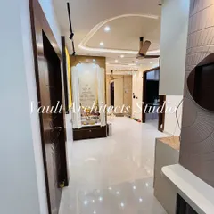 A view down the hallway of a newly completed apartment. This image captures the cohesive design language, from the polished floors and elegant pooja mandir to the textured wall panels in the living area.