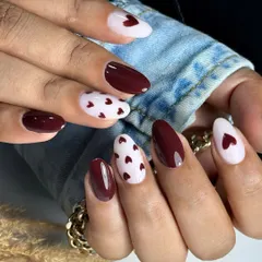 A lovely combination of deep dark maroon and milky white nails, with accent nails featuring tiny, hand-painted hearts for a romantic and chic look.