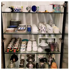 This crockery cabinet is organized for a client who loves to host. We used shelf risers to double the storage space and grouped items like mugs, plates, and teapots for easy access.