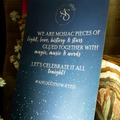 A beautifully designed welcome sign for a starry night sangeet with a romantic quote: "We are mosaic pieces of light, love, history & stars, glued together with magic, music & words."