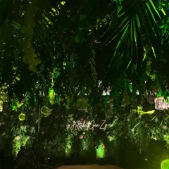 A stunning entrance designed to feel like a lush, tropical jungle. We covered the walls and ceiling with dense greenery and used a custom neon sign to welcome guests to this wild and chic cocktail party.