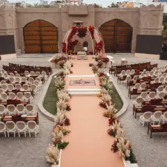 An aerial view of a wedding ceremony at Fairmont Jaipur, showing the grand scale and symmetry of the layout. The design blends traditional red florals with earthy pampas grass for a modern royal aesthetic.
