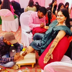 For larger events, my team and I can apply mehndi for many guests at once. Here you can see us working on both hand and foot designs for guests at a wedding celebration.