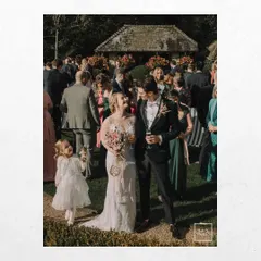 A candid moment from a wedding in Bibury, UK, with the couple mingling with their guests. The image captures the joyful, relaxed atmosphere of a garden party celebration.