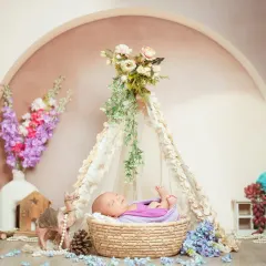 This teepee setup, adorned with delicate flowers, creates a beautiful bohemian vibe for a newborn session. It’s all about creating a peaceful and artistic portrait of your sleeping baby.