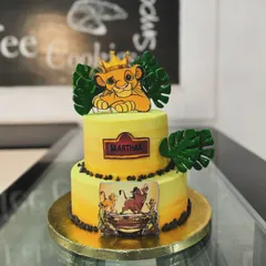 A two-tiered Lion King cake for a young fan. This design features Simba and other characters from the pride lands, decorated with edible leaves for a jungle feel.