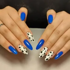 A bold combination of glossy royal blue and a classic black and white cow print on almond-shaped nails.