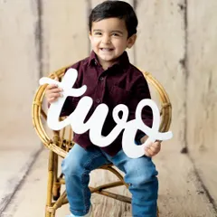 A proud two-year-old. This little boy's joyful smile is the highlight of his second birthday milestone photoshoot in our studio.