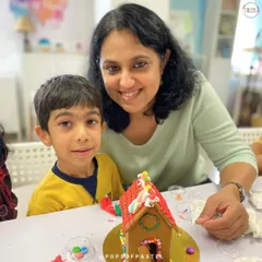 A mother and son duo proudly pose with their finished gingerbread house, a sweet memory from our holiday workshop.