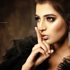 In this shot, the pose and expression are just as important as the makeup. The "shushing" gesture adds a layer of intrigue, making it a compelling image for a beauty or cosmetics campaign.