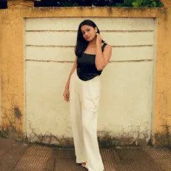 A full-body shot using a simple, textured wall as a clean background. This allows the model's outfit and pose to be the main focus of the portrait.