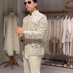 A modern and chic Indo-western outfit. This white jacket features unique cutwork detailing, worn over a simple kurta. It's a high-fashion look for the style-conscious groom or guest.