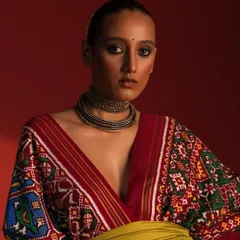 A close-up portrait from the same Ravissant series. This image focuses on the model's direct gaze, the intricate pattern of the V-neckline, and the stacked choker necklace, highlighting how beauty and accessory styling complete the look.