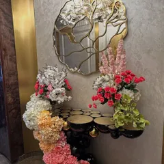 This home wedding decor features a stunning floral installation that flows from a console table and frames a doorway, using a beautiful ombre effect with pink, orange, and white flowers.
