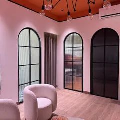 The waiting area in our design studio, featuring an industrial-style spider chandelier, modern arched doors, and comfortable boucle armchairs.