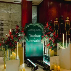 The welcome to Swathi and Tushar's Sangeet was moody and modern. A deep green sign was flanked by bold red tropical flowers and glowing candles, setting a dramatic and sophisticated tone.